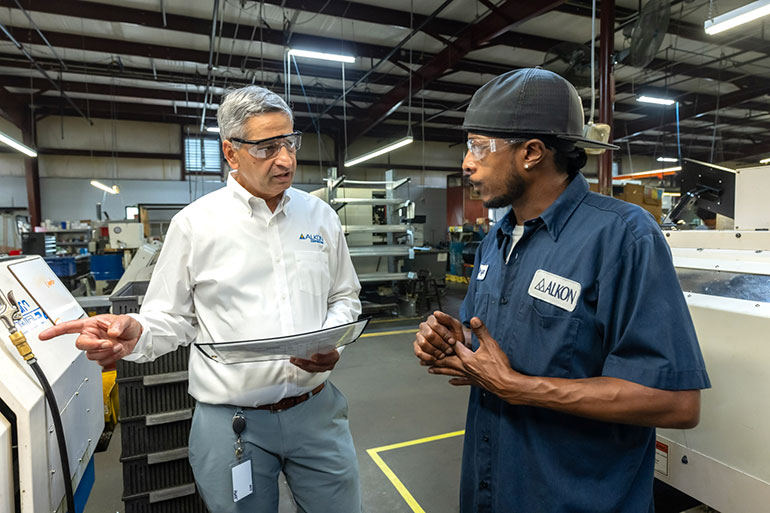 Alkon CEO Rahul Deshmukh speaks with Bryan Harvey, a member of the machining team, on the production floor.